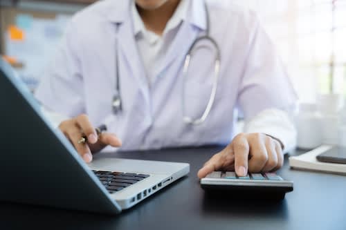Doctor typing on calculator