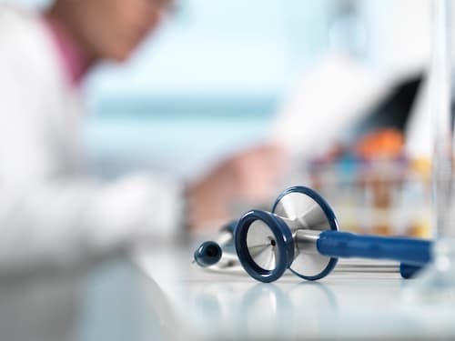 stethoscope-on-desk-doctor-in-background-2026-01-09-08-24-47-utc_arqzzh-IDEyCa