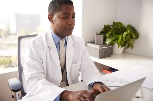 male-doctor-wearing-white-coat-in-office-sitting-a-2024-10-19-10-14-42-utc_byciga